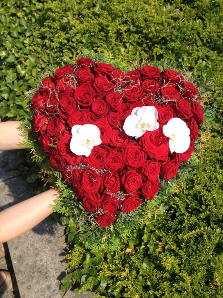 weiße Orchideen und rote Rosen als Herz gesteckt
